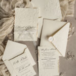 Ivory & Gold Elegance: Fine Art Embossed Wedding Invitations with Torn Edges, Floral Engraving, and Gilded Details