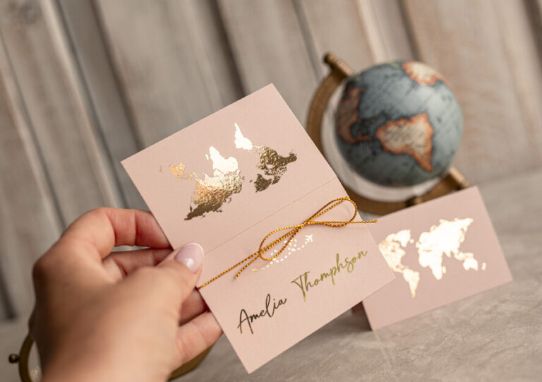 Create a luxurious and elegant wedding blog featured image inspired by blush pink travel-themed escort cards with gold foil world map details, delicate golden string bow, and modern calligraphy names. The scene should include sophisticated wedding stationery styling on a rustic wooden background with soft natural light, shallow depth of field, and romantic editorial photography aesthetics. Include a subtle luxury wedding atmosphere with refined textures, warm tones, and premium details. Generate an expert-level wedding blog article in English about “How to Create the Perfect Wedding Seating Arrangement.” The article should sound professional, modern, and elegant, offering practical expert advice for couples planning their wedding reception seating chart. Cover topics such as organizing guests by relationships and personalities, avoiding awkward table combinations, balancing family and friends, seating elderly guests comfortably, managing children’s tables, choosing between sweetheart and head tables, and using escort cards as part of the wedding decor. The writing style should feel like a luxury wedding magazine or professional wedding planner blog. Include SEO-friendly headings, engaging introduction, and natural keywords related to wedding seating plans, escort cards, reception organization, and wedding guest experience.
